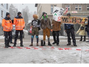 Climate activists pose beside Swiss police officers during a protest ahead of the World Economic Forum (WEF) 2023 in the Alpine resort of Davos, Switzerland, January 15, 2023.