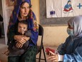 File - A Save the Children nutrition counsellor, right, explains to Nelab, 22, how to feed her 11-month-old daughter, Parsto, with therapeutic food, which is used to treat severe acute malnutrition, in Sar-e-Pul province of Afghanistan, Thursday, Sept. 29, 2022. (Save the Children via AP, File)