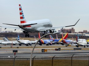 An American Airlines jet lands in front of planes backed up waiting to depart on the runway after flights earlier were grounded during an FAA system outage at Laguardia Airport in New York City, New York, U.S., January 11, 2023.