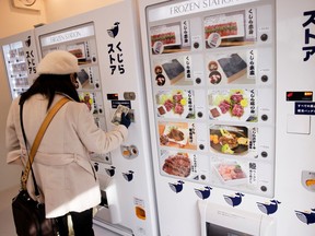 A customer buys whale meat on the opening day of the shop by a Japanese whale-hunting company with vending machines, in Yokohama, Japan, Jan. 24, 2023.