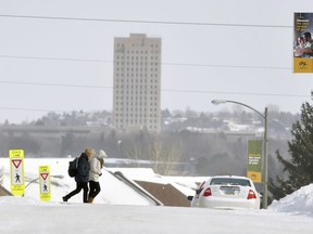 FILE - In this Feb. 7, 2019 file photo, pedestrians walk across the Bismarck, N.D. campus The state Capitol building is seen in the background. As more than a dozen states consider passing anti-transgender legislation this year, North Dakota lawmakers are diving into a bill that would make people pay $1,500 each time they refer to themselves or others with gender pronouns different from the ones they were assigned at birth.
