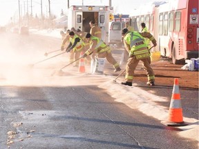 L'escouade des matières dangereuses du Service des incendies d'Ottawa (hazmat) répand des matières sur la surface de la route pour contenir le carburant diesel qui s'est échappé du réservoir de carburant rompu de l'autobus d'OC Transpo impliqué dans la collision de samedi.