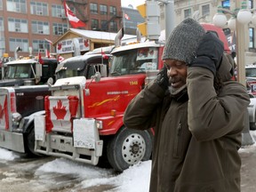 OTTAWA - Feb 3, 2022 - Anti vaccine mandate protesters and truckers protesting their seventh day in downtown Ottawa Thursday. A man covers his ears while passing honking trucks on Wellington Street Thursday. TONY CALDWELL, Postmedia.