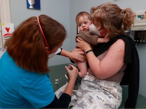 Dr. Nili Kaplan-Myrth, left, gives a COVID shot to Fredrik (9 months) in Ottawa before Christmas.