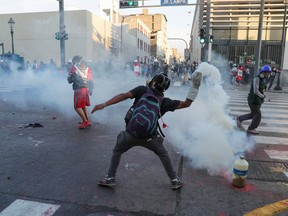 A demonstrator throws back a tear gas canister during an anti-government demonstration following the ouster of Peru's former President Pedro Castillo, in Lima, Peru, Jan. 24, 2023.