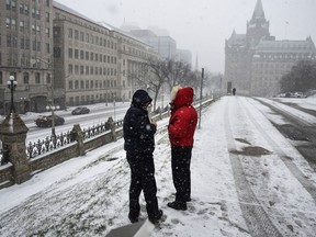 People keep warm in their winter coats as they vape outside Parliament Hill's West Block as snow falls in Ottawa, on Wednesday, Dec. 15, 2021. Advocates on both sides of the vaping debate say the government must do more to enforce penalties for selling vapes to kids after a review concluded no changes to the legislation were warranted.