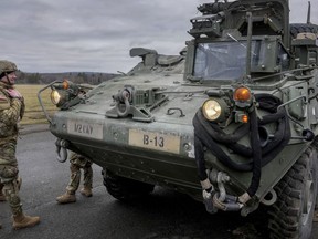 FILE - Soldiers of the 2nd Cavalry Regiment stand next to a Stryker combat vehicle in Vilseck, Germany, Wednesday, Feb. 9, 2022. The U.S. is finalizing a massive package of military aid for Ukraine that U.S. officials say is likely to total as much as $2.6 billion. It's expected to include for the first time nearly 100 Stryker combat vehicles and at least 50 Bradley fighting vehicles to allow Ukrainian forces to move more quickly and security on the front lines.