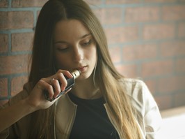 Vaping teenager. Young white girl smokes an electronic cigarette  in vape bar. Bad habit