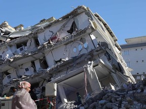 A woman stands in front of a a collapsed building in Islahiya, in the hard hit region of Gaziantep, after a 7.8 magnitude earthquake struck the border region of Turkey and Syria. (Photo by Zein Al RIFAI / AFP)
