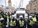 Polisi menggantung truk saat pihak berwenang bekerja untuk mengakhiri protes terhadap tindakan COVID-19 yang telah berkembang menjadi demonstrasi dan pendudukan anti-pemerintah yang lebih luas yang berlangsung selama berminggu-minggu, di Ottawa, Sabtu, 19 Februari 2022.