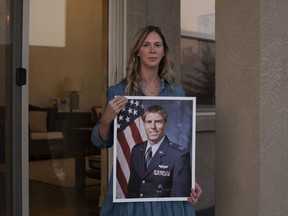 Jenny Holmes poses with a photo of her husband, Mark Holmes, at her home in Colorado Springs on Thursday.