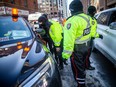 Ottawa Police Service officers accompany city by-law officers in the "red zone" during the convoy protest last February.
