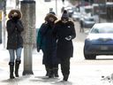 Women trying to stay warm on Metcalfe Street in freezing temperatures in Ottawa Friday.