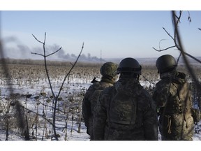 Ukrainian soldiers watch as smoke billows during fighting between Ukrainian and Russian forces in Soledar, Donetsk region, Ukraine, Wednesday, Jan. 11, 2023.