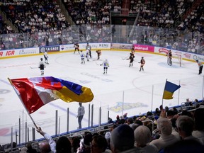 Supporters of Ukrainian Team Select wave flags during the team opening appearance at the Quebec International Pee-Wee Hockey Tournament in Quebec City on Feb. 11, 2023.