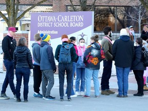Quelques-unes des dizaines de personnes qui attendent à l'extérieur avant une réunion du conseil scolaire du district d'Ottawa-Carleton mardi soir.
