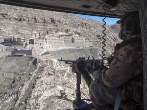 A Canadian Forces door gunner keeps watch as his Griffon helicopter passes the Monastery of Mar Mattai/St Matthew, in northern Iraq, Feb. 20, 2017. Canada is extending a scaled-down version of its military mission in Iraq and the Middle East for another two years.