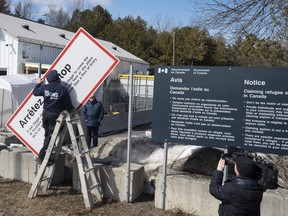 Workers remove warning signs at the illlegal Roxham Road border crossing on March 24.