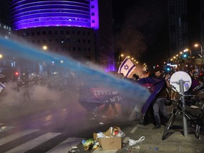 Israeli security forces use water canons to disperse protesters during ongoing demonstrations in Tel Aviv on March 27, 2023. - Israel's Prime Minister Benjamin Netanyahu on the night of March 27, 2023, paused a judicial overhaul which triggered a general strike, political division and mass protests in the country's most severe domestic crisis in years.