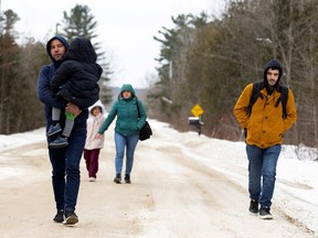Asylum-seekers walk down Roxham Road to cross into Canada from the U.S. in Champlain, New York, Feb. 25, 2023. Canada has legally committed to protect refugees even if they have gained access to the country unlawfully.