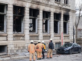 Investigators and firefighters are shown at the scene following a fire in Old Montreal on Saturday, March 18, 2023, that gutted the heritage building. The blaze caused structural damage to the heritage building and it’s too dangerous for investigators to look for victims, so on Sunday morning, crews will be brought in to take apart the facade of the second and third storeys of the building, constructed in 1891.