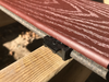 Composite deck lumber looks best when secured with hidden fasteners. Here a clip is being used to secure a composite deck board, with this clip hidden by the next board to go down.