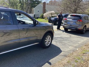 Vehicles move through a police blockade on a road in North Dighton, Mass., Thursday, April 13, 2023. The FBI wants to question a 21-year-old member of the Massachusetts Air National Guard in connection with the disclosure of highly classified military documents on the Ukraine war, two people familiar with the investigation said.