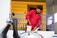 A young man in India takes the battery out from an electric scooter.