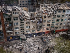 This aerial view shows rescuers on top of a partially destroyed residential building, after a shelling in Sloviansk, on April 14, 2023, amid Russia's military invasion on Ukraine. - Russian shelling of a residential building in the eastern Ukrainian city of Sloviansk killed at least five people on April 14, the local governor said.