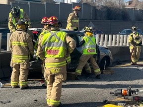 Firefighters extricate a passenger from a car in a crash on Highway 417 near Parkdale Avenue, Friday, April 28, 2023.