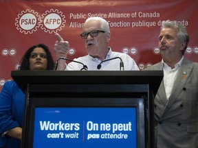 Public Service Alliance of Canada national executive vice-president Sharon DeSousa, left, and Quebec regional executive vice-president Yvon Barriere look on as national president Chris Aylward makes a point during a news conference at union headquarters in Ottawa.