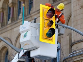 A City of Ottawa worker helps reinstall traffic lights on Wellington Street in front of Parliament Hill in this photo taken Thursday.