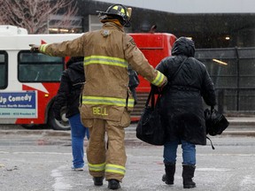 Ottawa's LRT shut down due to a power issue Apr. 5 as a freezing rainstorm hit the capital. Ottawa Fire Fighters and Ottawa Police cut a hole in the fence near Lees Station to help get riders evacuated off the train. A firefighter helps a lady in the freezing rain Wednesday.