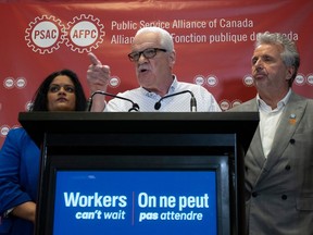 Public Service Alliance of Canada National Executive Vice-President Sharon DeSousa (left) and Quebec Regional Executive Vice-President Yvon Barriere look on as National President Chris Aylward makes a statement during a news conference at union headquarters on Monday in Ottawa.