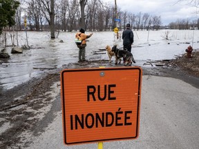 People look at the rising waters of the Milles-Iles river in Laval, Que., Tuesday, April 18, 2023. Regions across the province are on increased flood alert as the spring thaw continues.