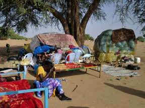 Asmaa, 19, a Sudanese refugee, combs her hair as she sits beside her family belongings near the border between Sudan and Chad in Koufroun, Chad.