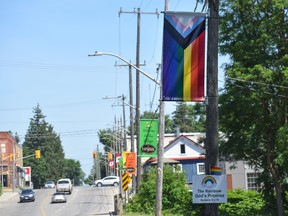 A Progress Pride banner hangs outside The Home Hardware on Stover Street in Norwich, a rural township east of London. A small sign mounted to the pole includes a Bible reference that reads: "The Rainbow God's Promise. Genesis 9 v 16." The banner is one of two that were reinstalled after multiple were stolen.