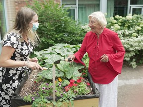 Long-term care resident Nicole Arranz enjoys the garden in a Perley Health courtyard accompanied by Kayleigh York, a staff member from the Ozerdinc Grimes Family Therapeutic Recreation and Creative Arts Program.  SUPPLIED PHOTO