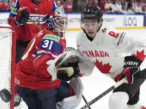 Cody Glass of Canada, right, fights for a puck with goalie Jonas Arntzen of Norway during the group B match between Canada and Norway at the ice hockey world championship in Riga, Latvia, Monday, May 22, 2023.