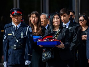 The wife of slain Const. Andrew Hong, Jenny, holds his hat, at the end of his funeral in Toronto on Sept. 21, 2022. Behind are daughter Mia, 17, and son Alex, 15, at the Toronto Congress Centre. Ernest Doroszuk/Postmedia