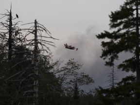 A water bomber plane flies through heavy smoke as an out-of-control wildfire in a suburban community outside of Halifax quickly spread, engulfing multiple homes and forcing the evacuation of local residents on Sunday, May 28, 2023. The wildfire that has destroyed dozens of homes in suburban Halifax could have been caused by a combination of factors, including a string of dry days, lack of rain and debris left behind by post-tropical storm Fiona last year, say experts.