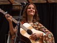 A photo of inger-songwriter Sofia Duhaime holding a guitar on stage.