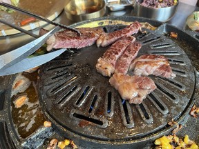 Guests use tongs and special meaet shears to turn and cut their barbecued meats at Daldongnae Korean BBQ on Somerset Street West