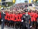 Thousands of officers march ahead of the hearse carrying Sgt. Eric Mueller to his funeral at the Canadian Tire Centre in Ottawa Thursday morning. The funeral procession, which travelled from Rockland to Kanata, was expected to have about 9,000 police in attendance. 
