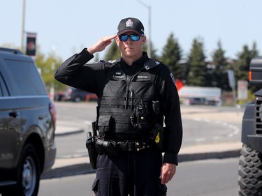 An officer salutes by the side of the road as the hearse carrying Sgt. Eric Mueller to his funeral at the Canadian Tire Centre in Ottawa Thursday morning passes by. The police officer was killed when responding to a call in Bourget in the early-morning hours of May 11th, along with two other officers who were wounded at the same time.