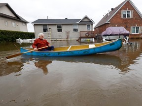 Dan Larrivée canoes past his house on Leo Lane in Cumberland Thursday. Dozens of homes are surrounded by water coming from the Ottawa River.