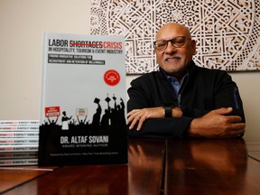 Local academic Altaf Sovani has poses in front of his book about the current labor crisis facing hotels and restaurants