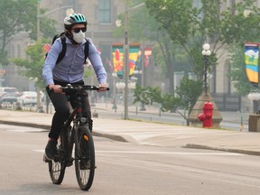 A cyclist wears a mask due to poor air quality conditions as smoke from wildfires in Ontario and Quebec hangs over Ottawa on Tuesday, June 6, 2023.