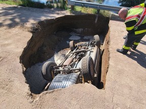 Rescuers inspect an overturned Jeep trapped in a sinkhole near Brighton, Colo.