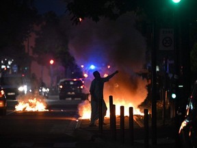 A man walks past a bonfire in a residential area during clashes in Toulouse, southwestern France on June 28, 2023, a day after the killing of a 17 year old boy in Nanterre by a police officer's gunshot following a refusal to comply.